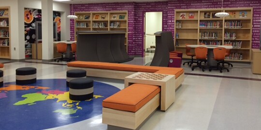 Una biblioteca tiene una gran lámina gráfica del globo terráqueo en el piso.
