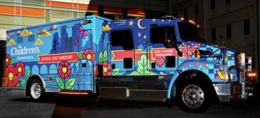 Imagen de un camion ploteado con dibujo de una ciudad oscura y flores rosas, amarillas y verdes.

