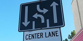 Stacked road signs, one depicting two driving lanes and one turn lane, and the other with the words “center lane.”
