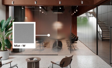 Imagen de una moderna sala de conferencias de oficina con colores cálidos, suelos de piedra y vegetación, y mención del producto acabado de cristal Mist.
