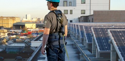 Worker on building roof connected to permanent rail anchor system
