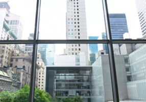 A view out a ground-floor window looks up at the New York skyline.