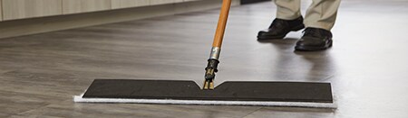 Primer plano de una fregona sobre suelos laminados de madera.
