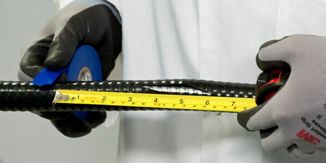 Manos aplicando cinta aislante blanca alrededor de un cable de cobre expuesto.

