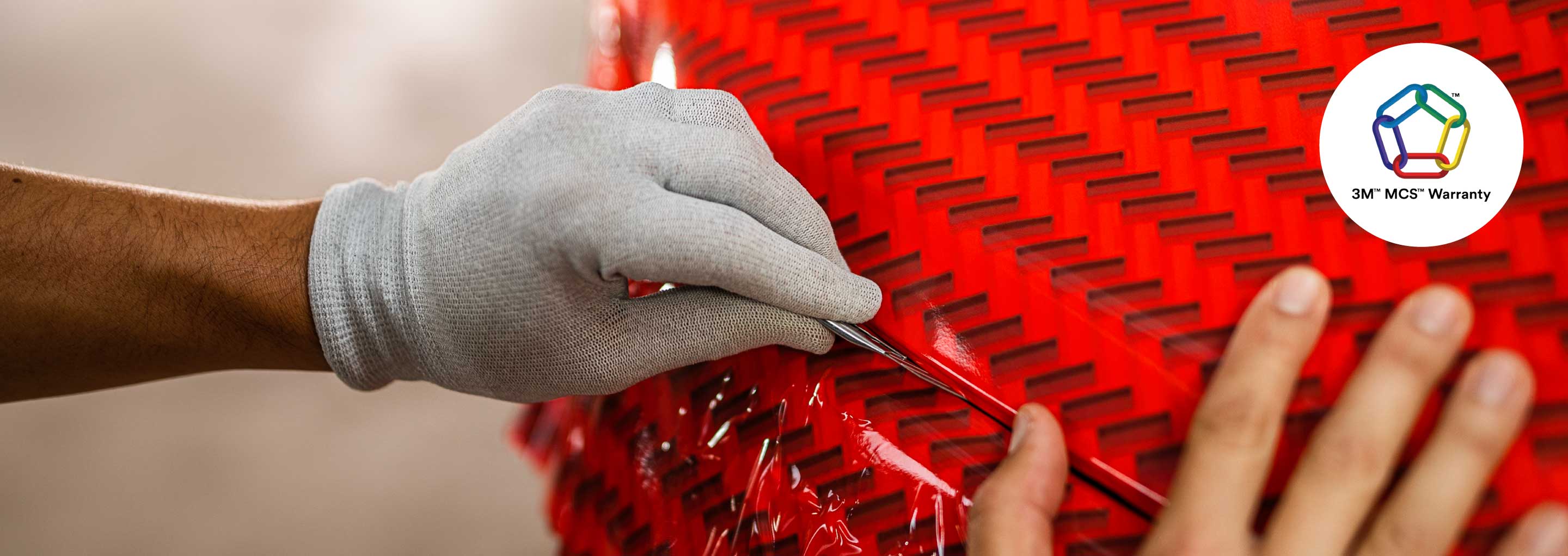 Imagen de un instalador colocando la lamina roja para plotear un vehículo.
