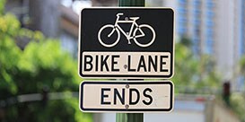 Black and white signs with image of bicycle and words “bike lane ends.”
