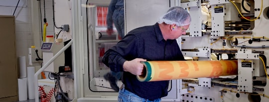 Image of a press operator inserting a cylinder into the press
