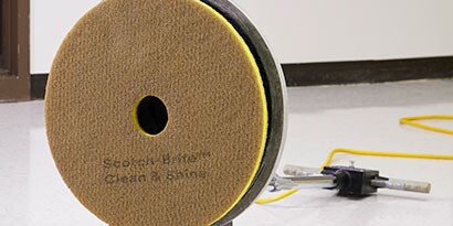Disco de piso 3M Clean & Shine en la parte inferior de una máquina de limpieza comercial.