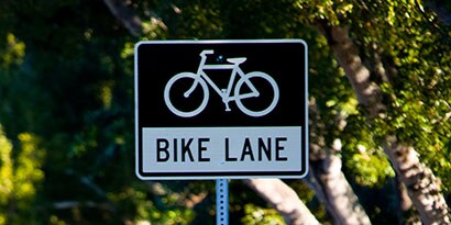 Black and white sign with image of bicycle and words “bike lane.”
