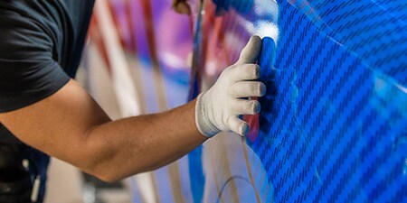 Instalador colocando película adhesiva azul sobre una camioneta.
