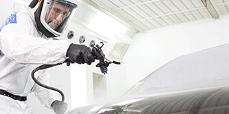 Técnico de pintura pulverizando vehículo.
