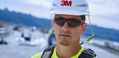 Image of a worker wearing a hard hat secured to his full body harness with a tether
