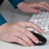 Man in warehouse on laptop completing an online medical evaluation