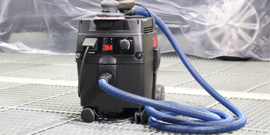 Extractora 3M con manguera azul conectada, situada en un taller automotriz.
