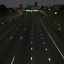 Fotografía nocturna de una autopista tomada desde arriba con marcas en el pavimento que muestran una reflectividad brillante.