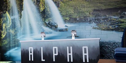 Imagen de la recepción de un local. Pared ploteada con cascadas y arboles
