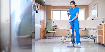 Una mujer limpiando el piso de una habitación de un hospital.
