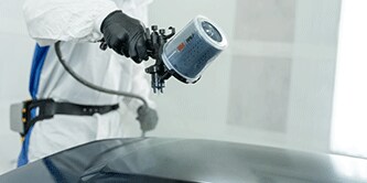 Técnico de pintura pintando veículo.
