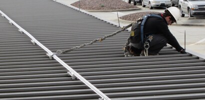 Worker on roof connected to permanently mounted rigid rail system
