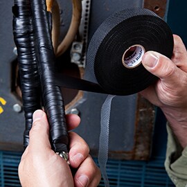Image of 3M™ Scotch® Vinyl Mastic Tape 2200 wrapping a low voltage cable in an irrigation hole.