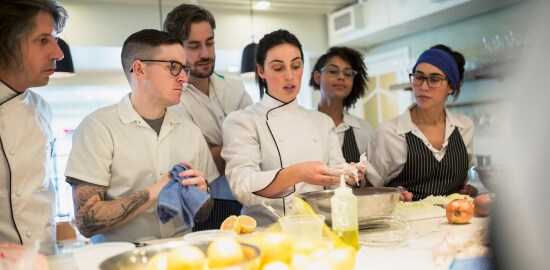 Una chef enseñando a sus cocineros.
