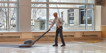 Hombre limpiando un piso con una máquina.
