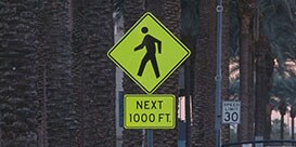 Yellow and black sign with image of pedestrian and words “next 1000 feet.”
