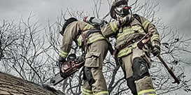 firefighters cutting into a house roof
