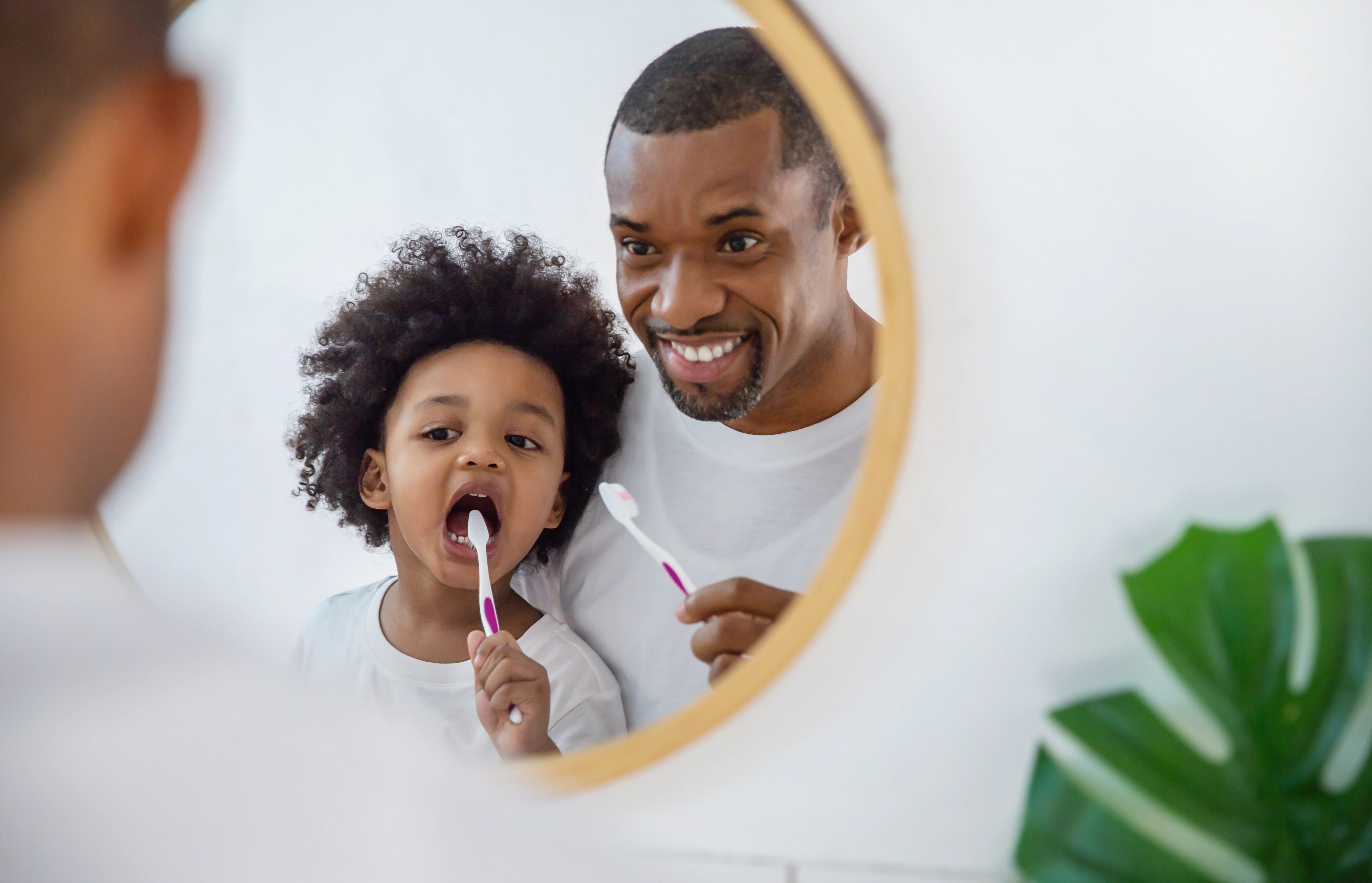 Padre e hija cepillando los dientes frente al espejo
