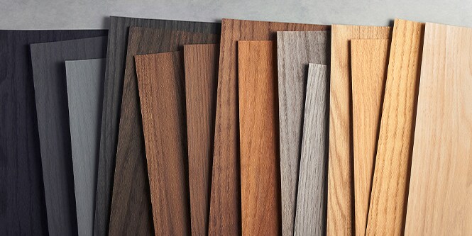 Imagen de muestras de vetas de madera DINOC de 3M organizadas por color, desde negro hasta tonos de madera claros.
