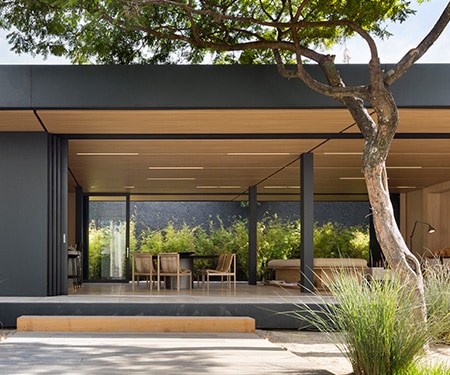 Exterior de una casa moderna con acabados en negro mate y madera clara.

